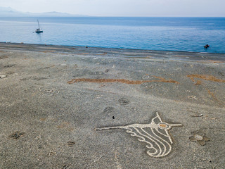 Vista aerea della spiaggia nera di sassi, Nonza, disegni geometrici fatti con i sassi, barche a...