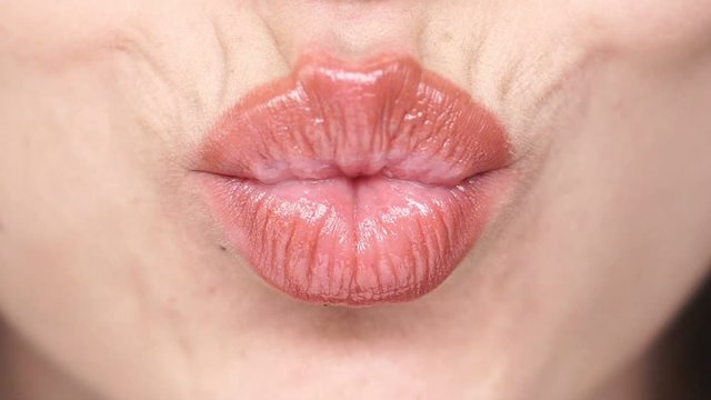 Close up view of female lips which sends air kiss and licking their