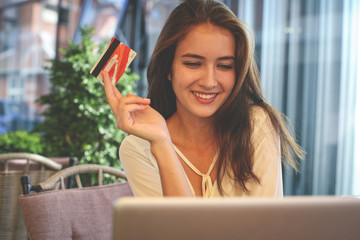 Young woman using lap top and credit card.