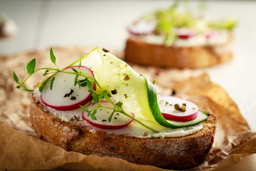Sandwich with red radish, cucumber and fresh herbs and pepper.