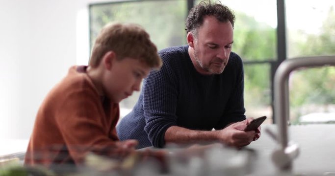 Father and Son in kitchen looking at smartphone