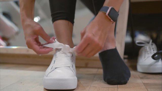 Young woman trying on white sneakers in a store