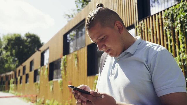 Handsom guy strolling on city street using online navigator to find right direction using modern smartphone