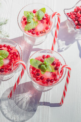 Cranberry drinks with lollipop candy cane on white rustic wooden table, Christmas background
