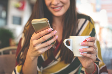 Happy woman using smart phone and holding cup of coffee. Close up.