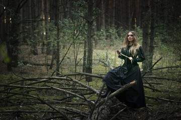 Halloween. beautiful girl in a black dress in the forest.