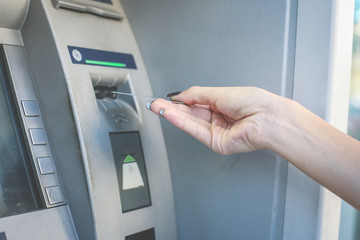 Hand of young girl using credit card on cash machine. Close up.