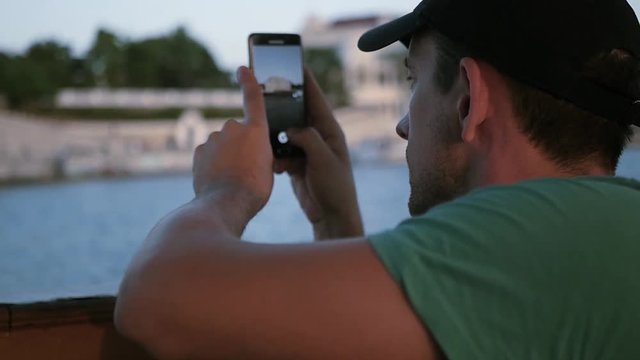 A man in a cap takes pictures of the city from the water to the phone. HD, 1920x1080. slow motion.