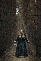 Fototapeta premium Halloween. beautiful girl with a lantern in a black dress in the forest.