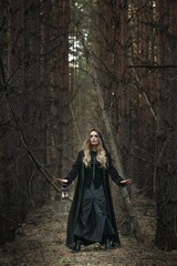 Halloween. beautiful girl with a lantern in a black dress in the forest.