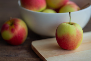Fuji apple on cutting board put on rustic wood table and stack in white bowl with copy space.Delicious sweet and juicy fuji apple suitable for salad cooking or bakery. Fuji apple has origins in Japan.