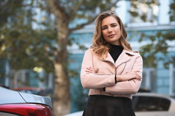 Young businesswoman portrait with crossed arms against office building background