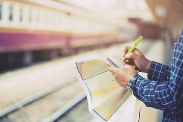 close up hand traveler looking the map, take notes in the notebook paper Plan before departure and Be ready to leave travel along with go to train. concept the tourist 