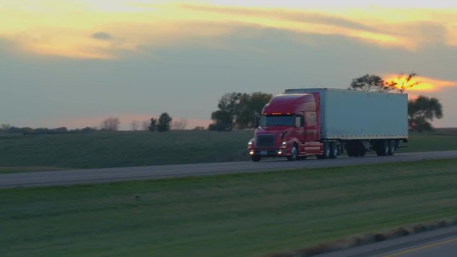 FPV: Driving along the busy heavy traffic highway running through scenic countryside at gorgeous morning in United States. People on road trip traveling, freight container semi trucks freighting goods