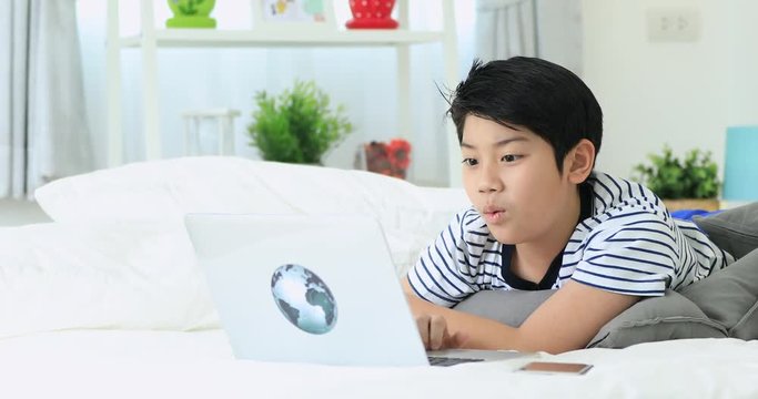 Cute asian boy hands typewriter on keyboard of laptop with smile face.