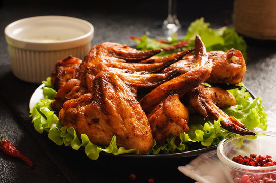 Grilled chicken wings with lettuce, dark background