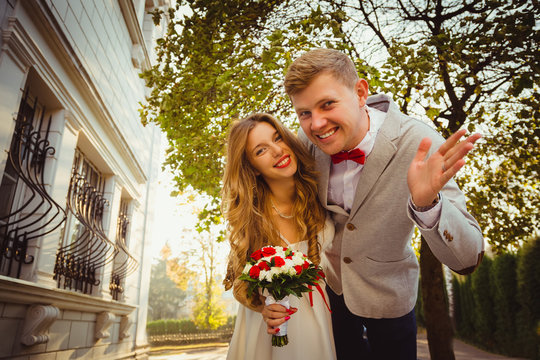 Couple waving hands and leaning to the camera with cheerful smil