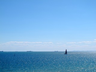Obraz premium view of sparkle sea water have sailboat on blue sky at Sandringham beach, Australia