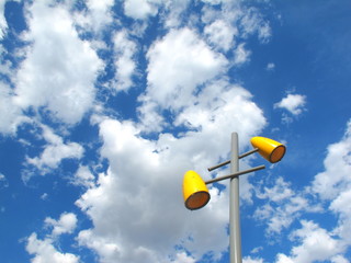 yellow lamp on the light pole in front of blue sky have white cloud