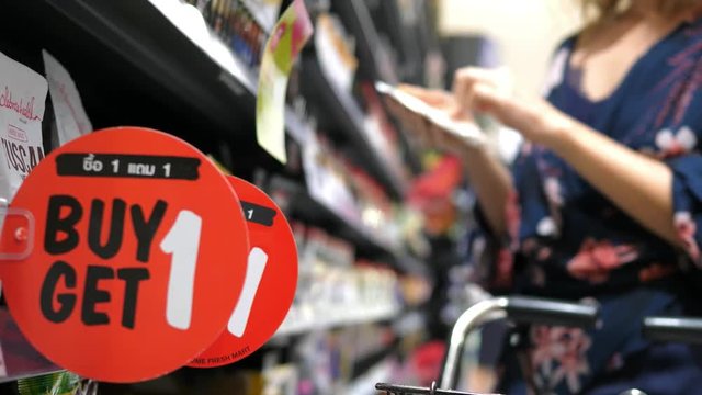 Woman Shopping In Supermarket With Buy One Get One Free Sale. Closeup. 4K. 