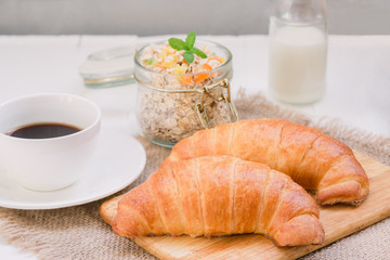 Continental traditional breakfast. Croissant, a cup of coffee and an granola. On a white background, on a canvas napkin