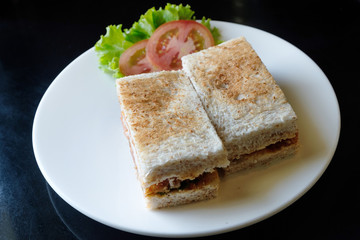 Healthy sandwich toast with lettuce, fried pork, cheese and tomato on a black marble background.