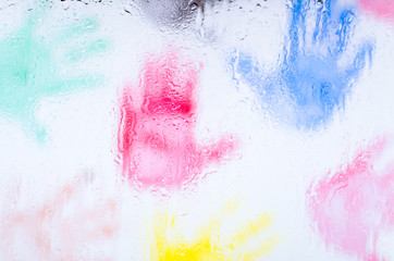 The prints of children's hands through wet glass