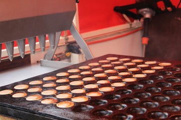 Making Dutch sweets Poffertjes with butter and sugar