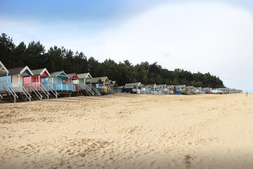 Row of beach huts on an empty, sandy Norfolk beach