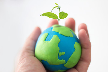 concept of earth day , hand holding earth with small plant
