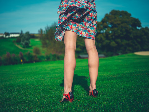 Woman standing on lawn with wind in dress