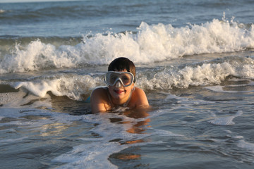 child plays in the sea wearing a diving mask