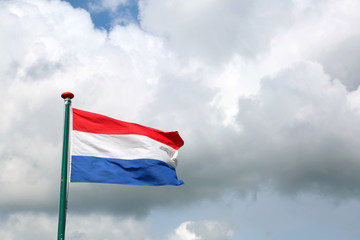 Fototapeta na wymiar flag of the Netherlands with red white and blue and cloudy sky