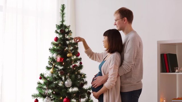 happy couple decorating christmas tree at home