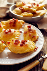  Baked dumplings stuffed with cheese and potatoes sprinkled with pork greaves  on a white plate