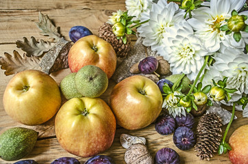 Apples,green nuts,figs and with prunes a bouquet of  white dahlias on wooden boards

