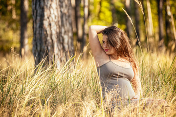 portrait of a beautiful young pregnant girl in a trendy dress against the background of an autumn forest