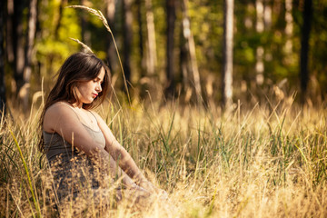 Naklejka na ściany i meble portrait of a beautiful young pregnant girl in a trendy dress against the background of an autumn forest
