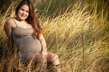 Naklejka na ściany i meble portrait of a beautiful young pregnant girl in a trendy dress against the background of an autumn forest