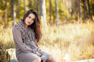 portrait of a beautiful young pregnant girl in a trendy dress against the background of an autumn forest