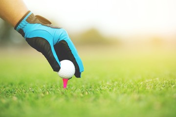 Close up of  Hand putting golf ball on tee in golf course on atmosphere Light sunshine.