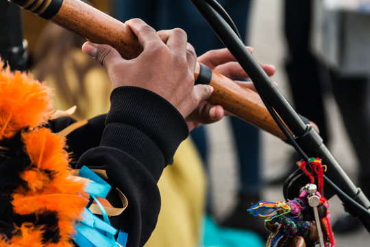 The hands of a street musician in a suit on an ethnic musical wind instrument made of bamboo.