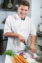 Portrait Of Chef Preparing Vegetables In Restaurant Kitchen