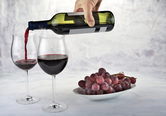 Two glasses of red wine with bottle and grapes