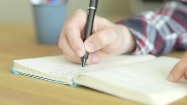 Close up of hands writing a to do list in a note book