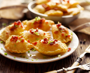 Baked dumplings stuffed with cheese and potatoes sprinkled with pork greaves and fresh herbs  on a...