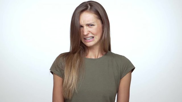 in slow motion lady with long brown hair expressing disgust saying no with facial expresions over white background. Concept of emotions 