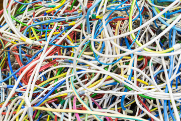 The bunch of electric wires of different colors are very much intertwined. On tangled wires is wire-end ferrules and markings. Chaos, confusion, tangle.