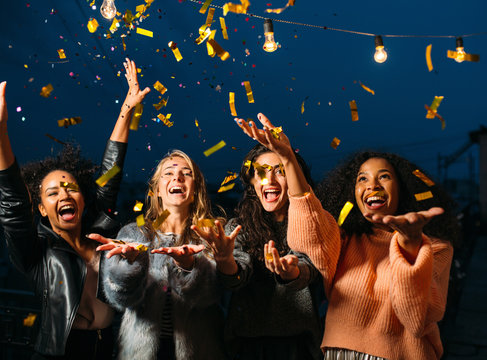 Happy Women Throwing Confetti In The Air. Friends Celebrating Outdoors.