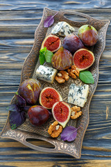 Figs with blue cheese and purple basil on a bronze tray.